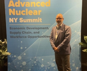 Charles stands in front of a poster at the Advanced Nuclear NY Summit.